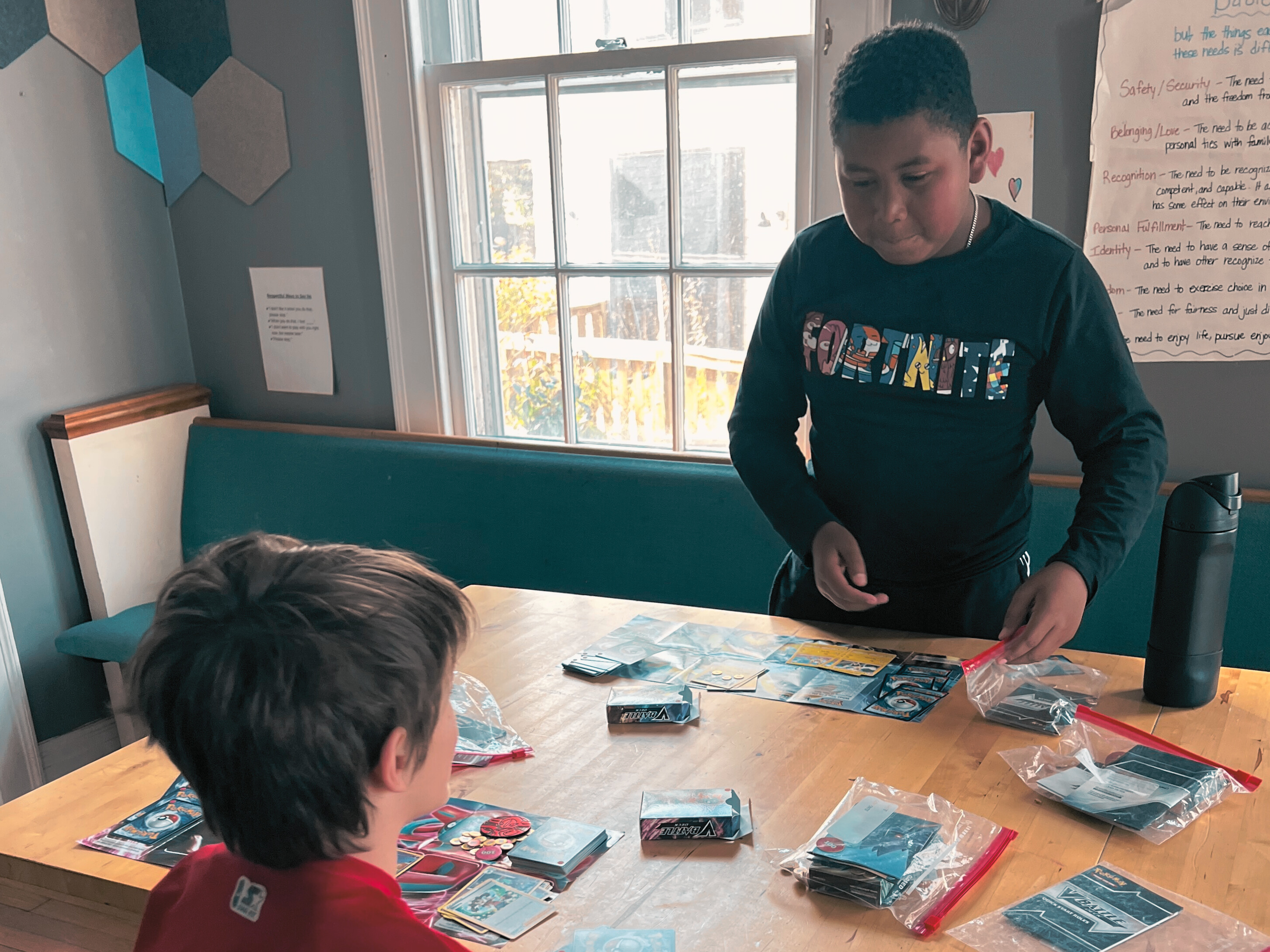 Child teaching another about Pokemon cards